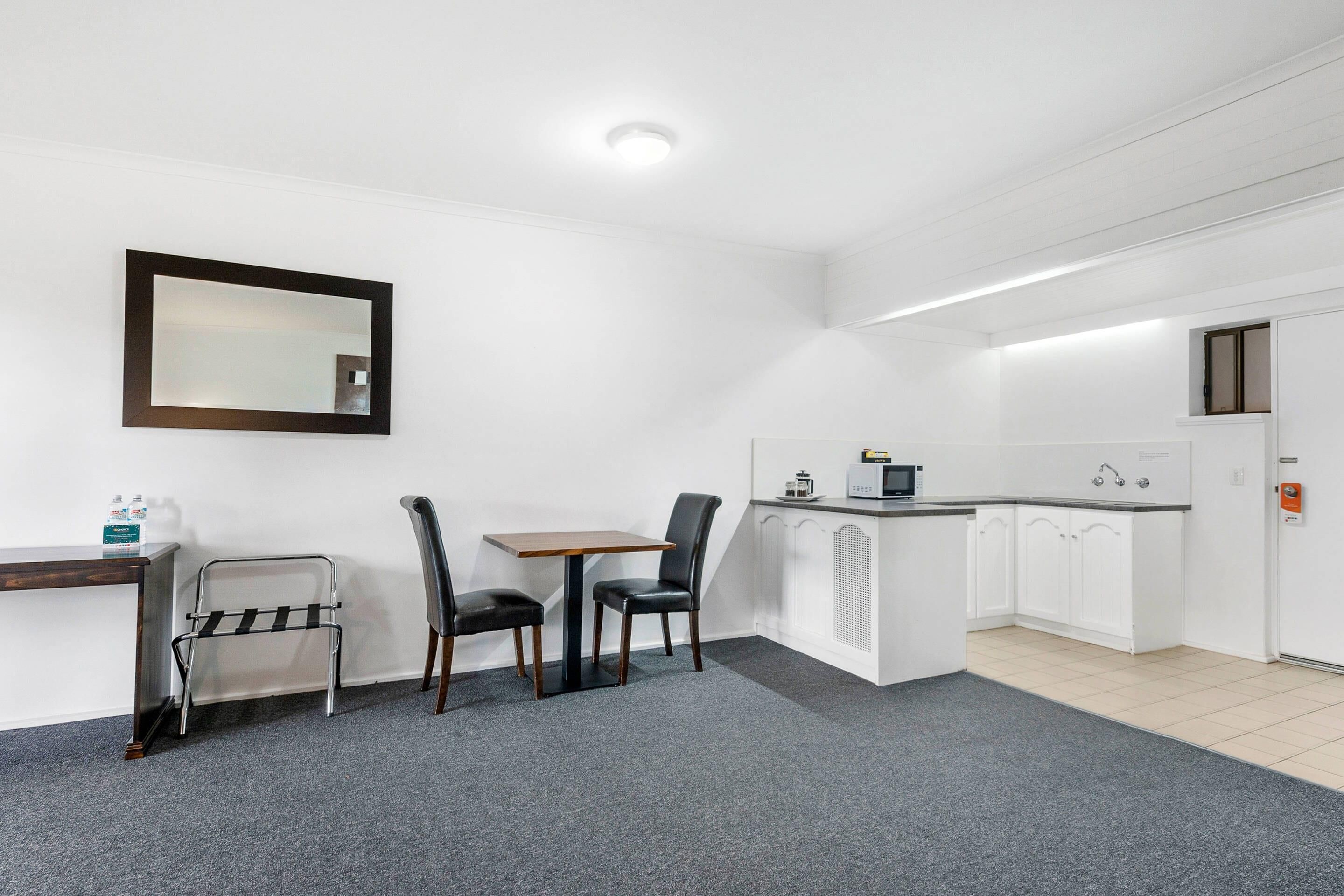 A compact kitchen with a dining area, a small table, two chairs, a microwave, and a sink.