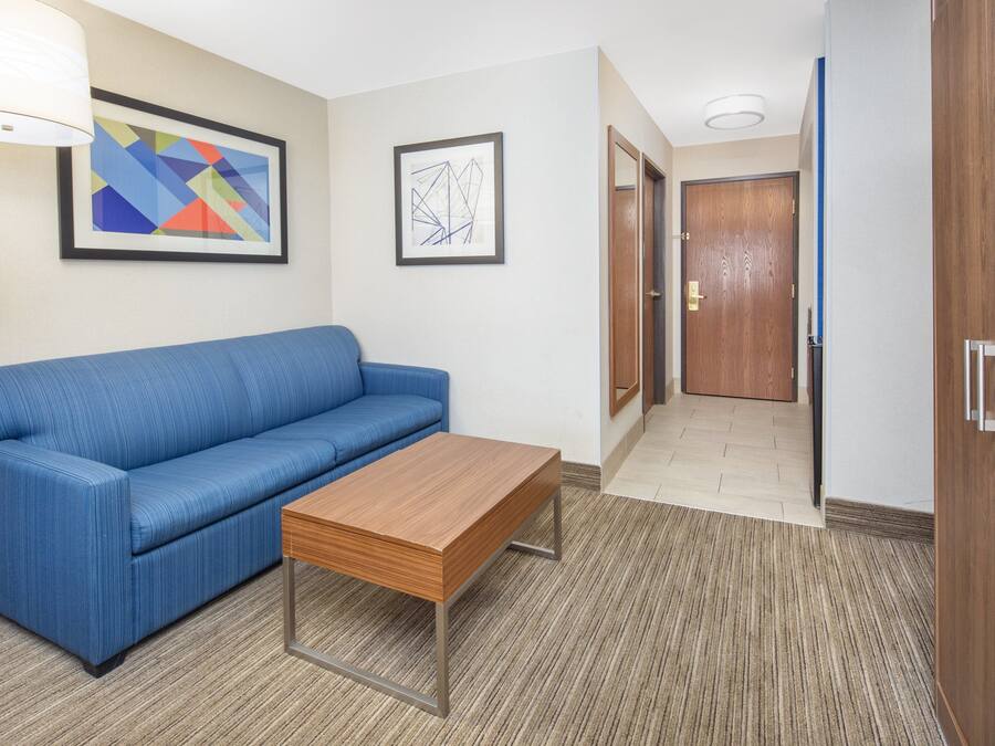 Ein Zimmer mit einem blauen Sofa, einem Holztisch und zwei gerahmten abstrakten Kunstwerken an der Wand.