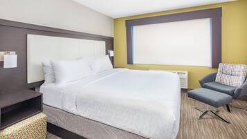 A hotel room with a large bed, a desk, a chair, and a window.