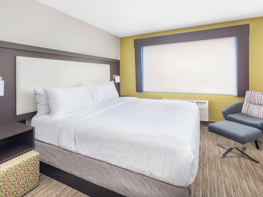 A hotel room with a large bed, a desk, a chair, and a window.