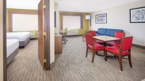 A hotel room with two beds, a desk, a table with red chairs, and a blue couch. - Holiday Inn Express Hotel & Suites Bishop by IHG (Bishop)
