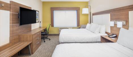 Habitación de hotel con dos camas, un escritorio, una silla, un televisor y una ventana con persianas.