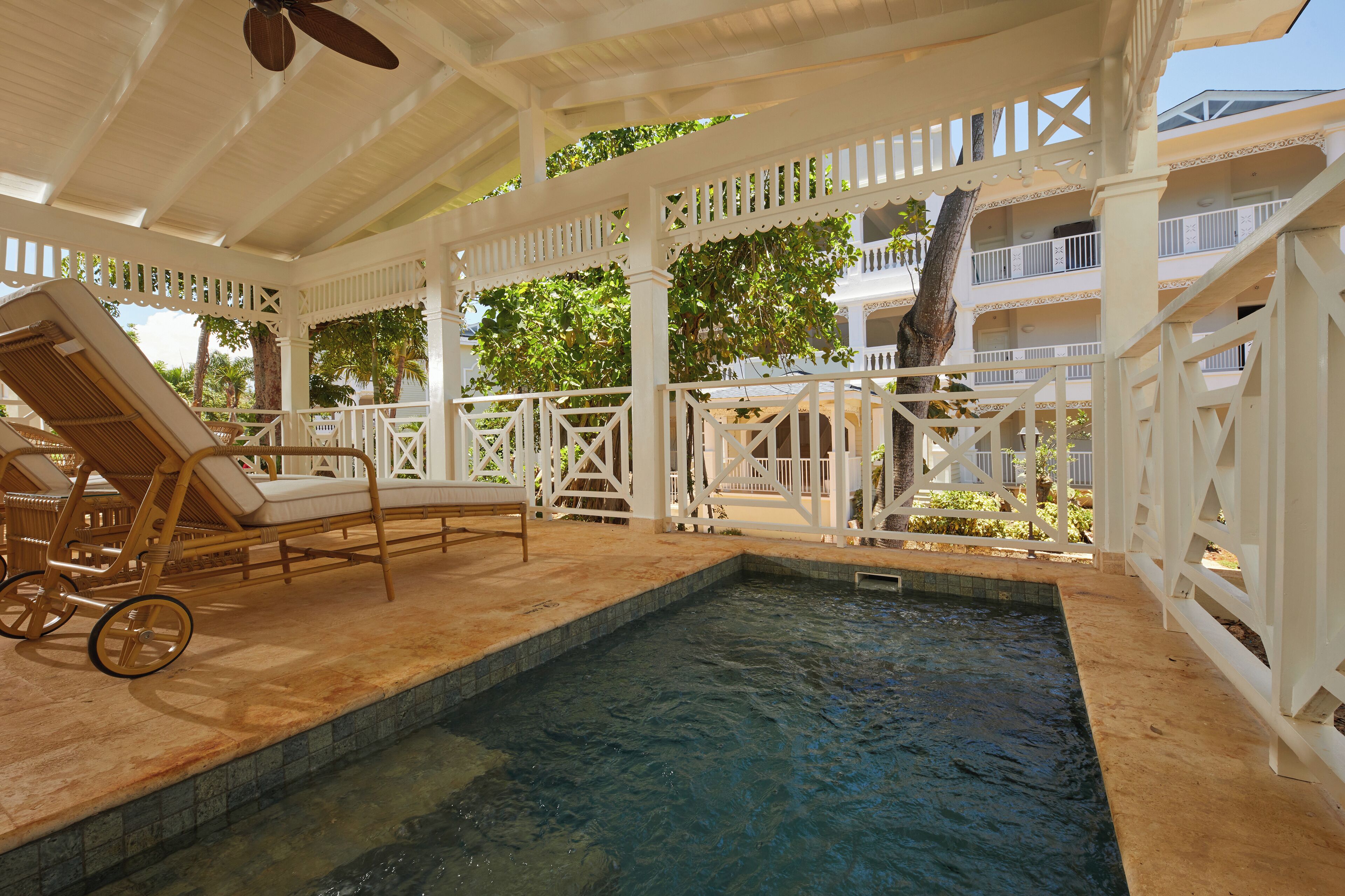 Un espace piscine couvert, équipé de chaises longues et d’un ventilateur de plafond.