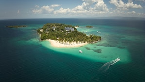 An aerial view of a tropical island with a beach, clear turquoise waters, and a few boats. - Cayo Levantado Resort - All Inclusive (Samaná)