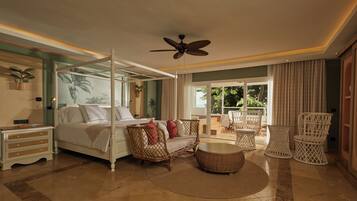 A spacious bedroom with a four-poster bed, a ceiling fan, and a balcony with wicker furniture.