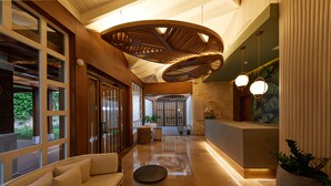 Spaziosa hall con reception, area salotto e un'ampia struttura in legno a soffitto.