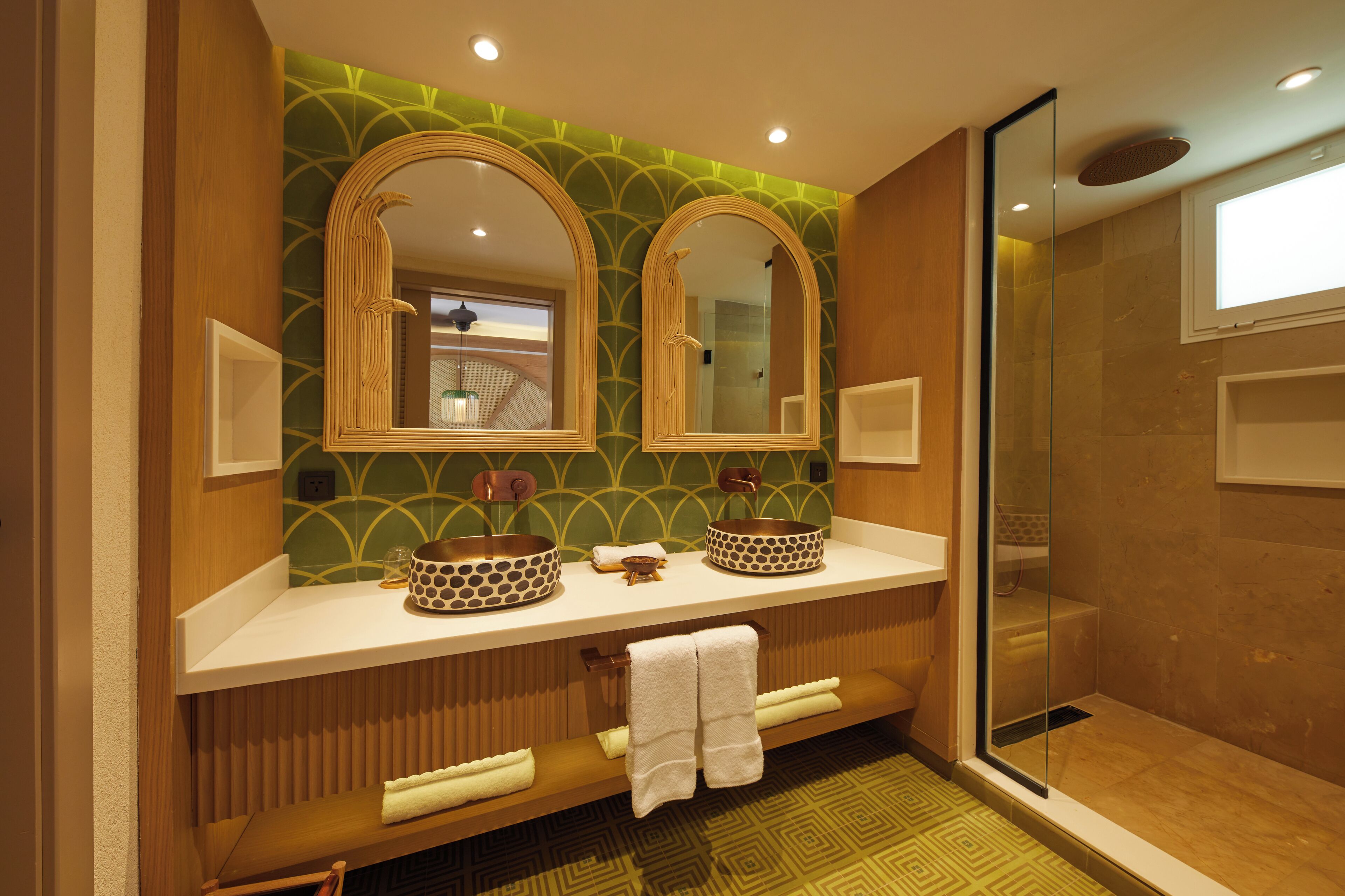 Un baño con dos espejos grandes, zona de ducha y tocador doble.