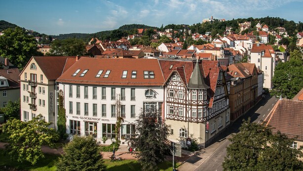 A historic hotel with a prominent clock tower, surrounded by traditional European architecture and lush greenery.