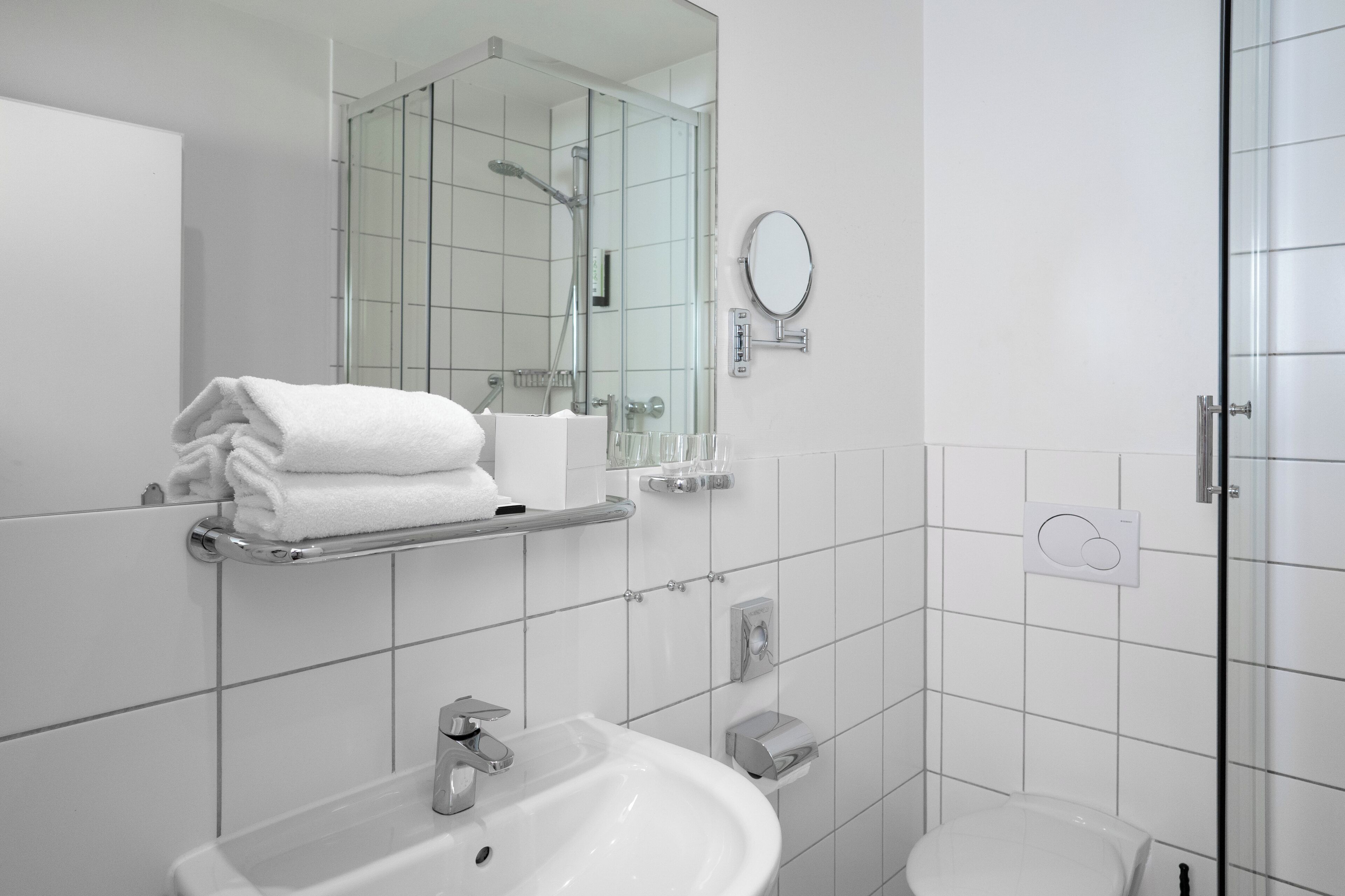 Een moderne badkamer met een wastafel, spiegel en douchecabine met glazen wanden.