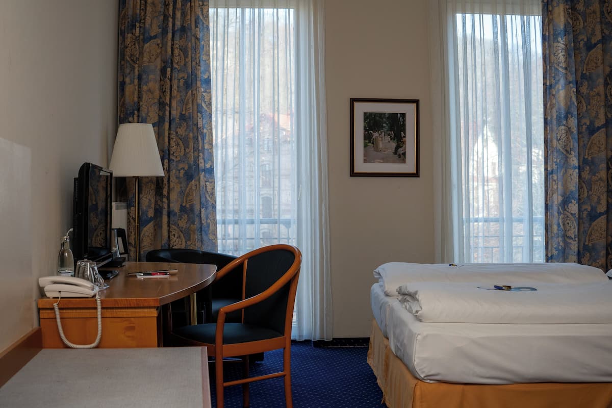 Una habitación de hotel con escritorio, silla, cama y un cuadro en la pared.