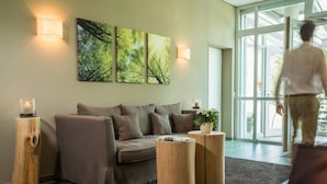 A modern living room with a sofa, two wooden side tables, and a large window.