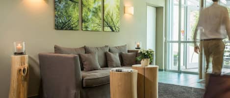 A modern living room with a sofa, two wooden side tables, and a large window.