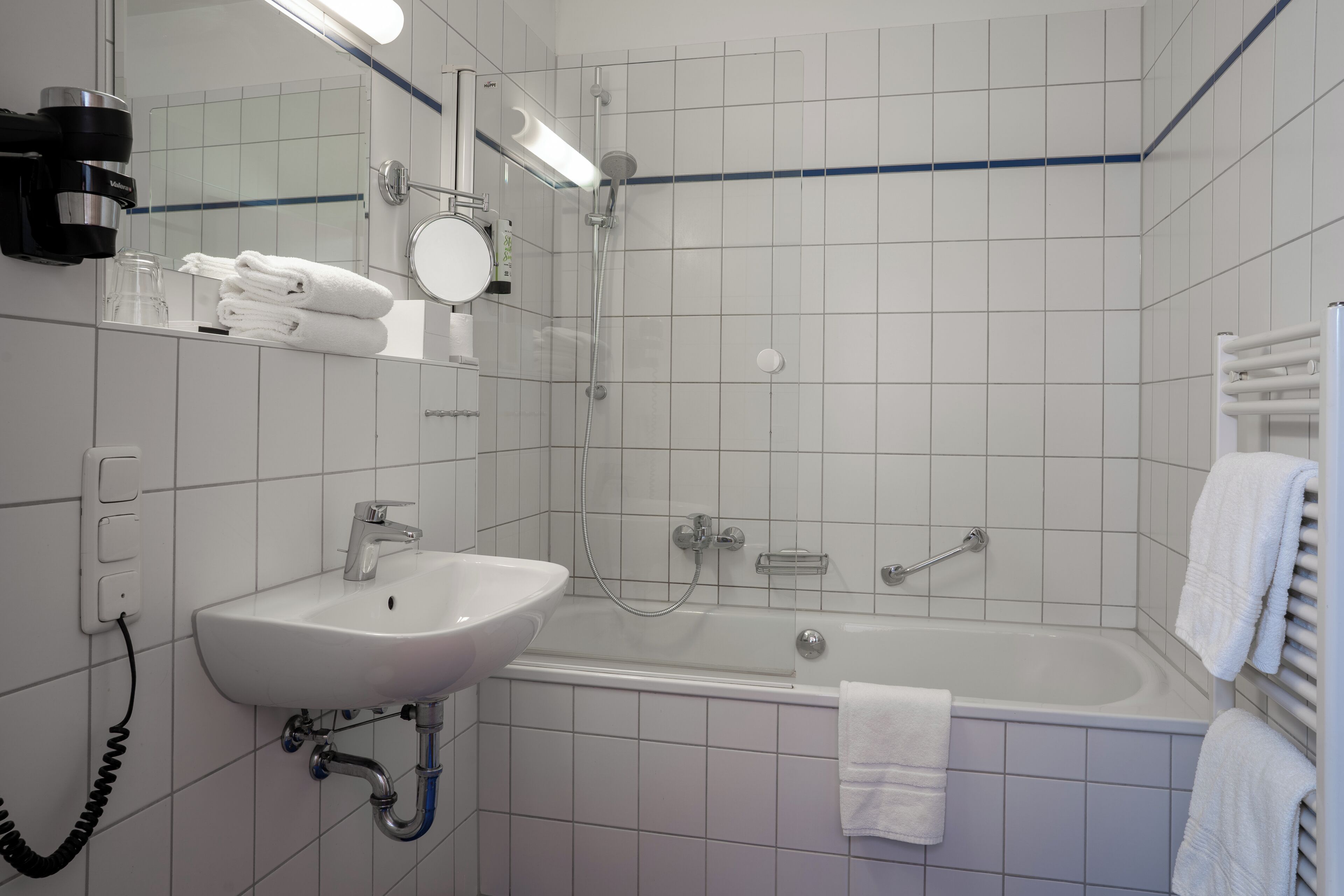A bathroom with a sink, mirror, towel rack, and shower.