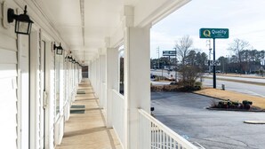 A covered outdoor corridor with a row of windows and a sign for Quality Inn. - Quality Inn Carrollton Medical Center (Carrollton)