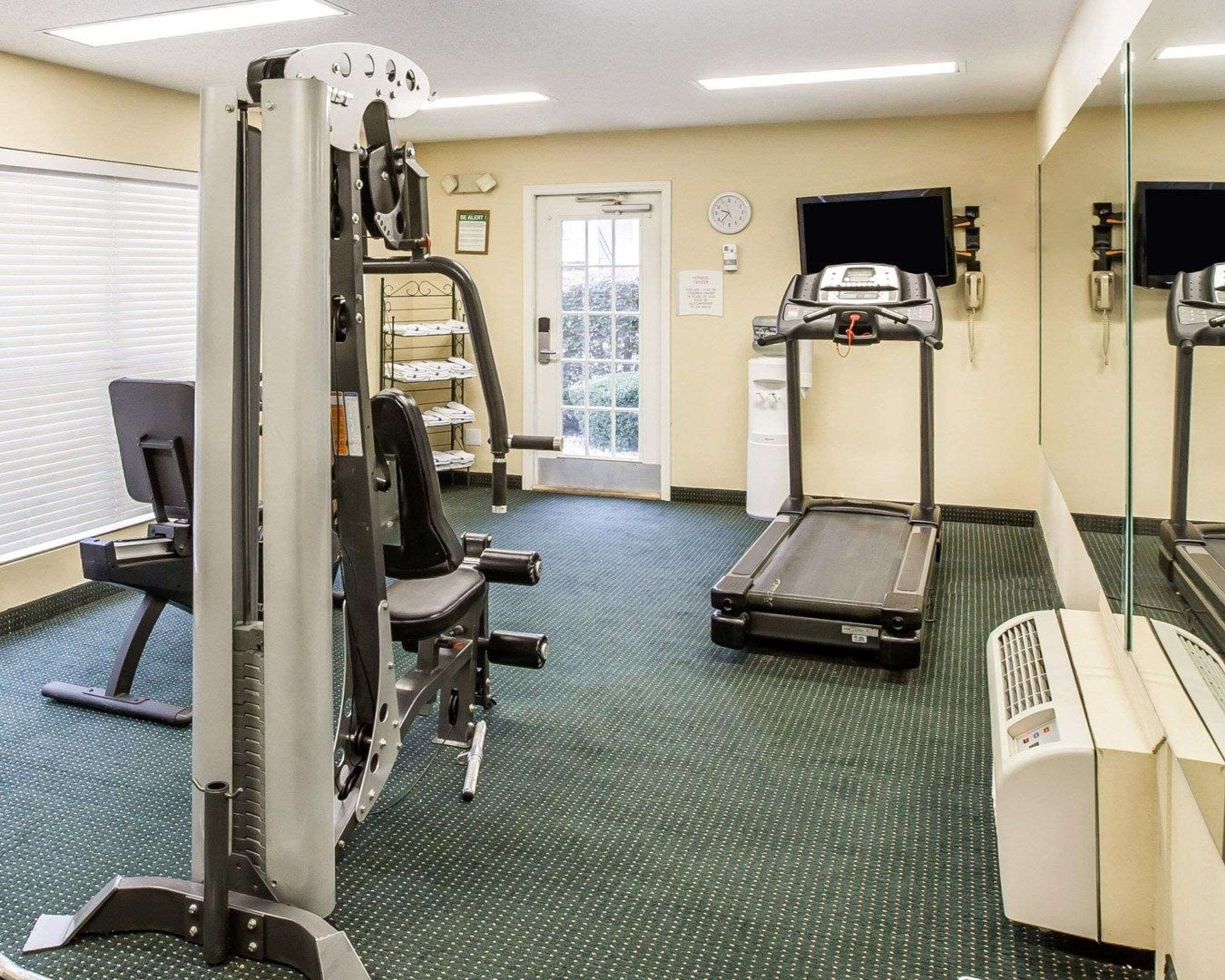 A fitness center with a treadmill, weight machine, and mirrored walls.