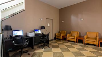 A hotel room with a desk, computer, two chairs, and a checkered floor.