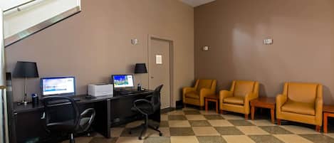 A hotel room with a desk, computer, two chairs, and a checkered floor.