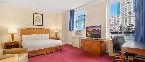 A hotel room with a bed, desk, chair, and a television.
