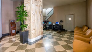 A lobby with a checkered floor, an ATM, a potted plant, a reception desk, computers, and a staircase. - Travelodge by Wyndham Downtown Chicago (Chicago)