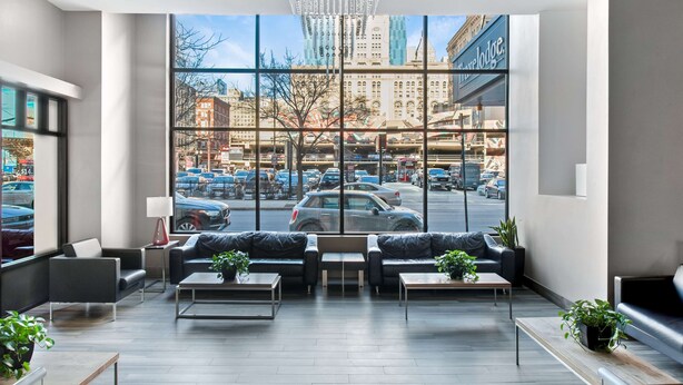 A modern hotel lobby with large windows, leather sofas, and a view of the cityscape. - Travelodge by Wyndham Downtown Chicago (Chicago)