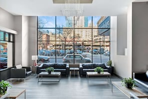 En moderne hotellobby med store vinduer, lædersofaer og udsigt over bybilledet.