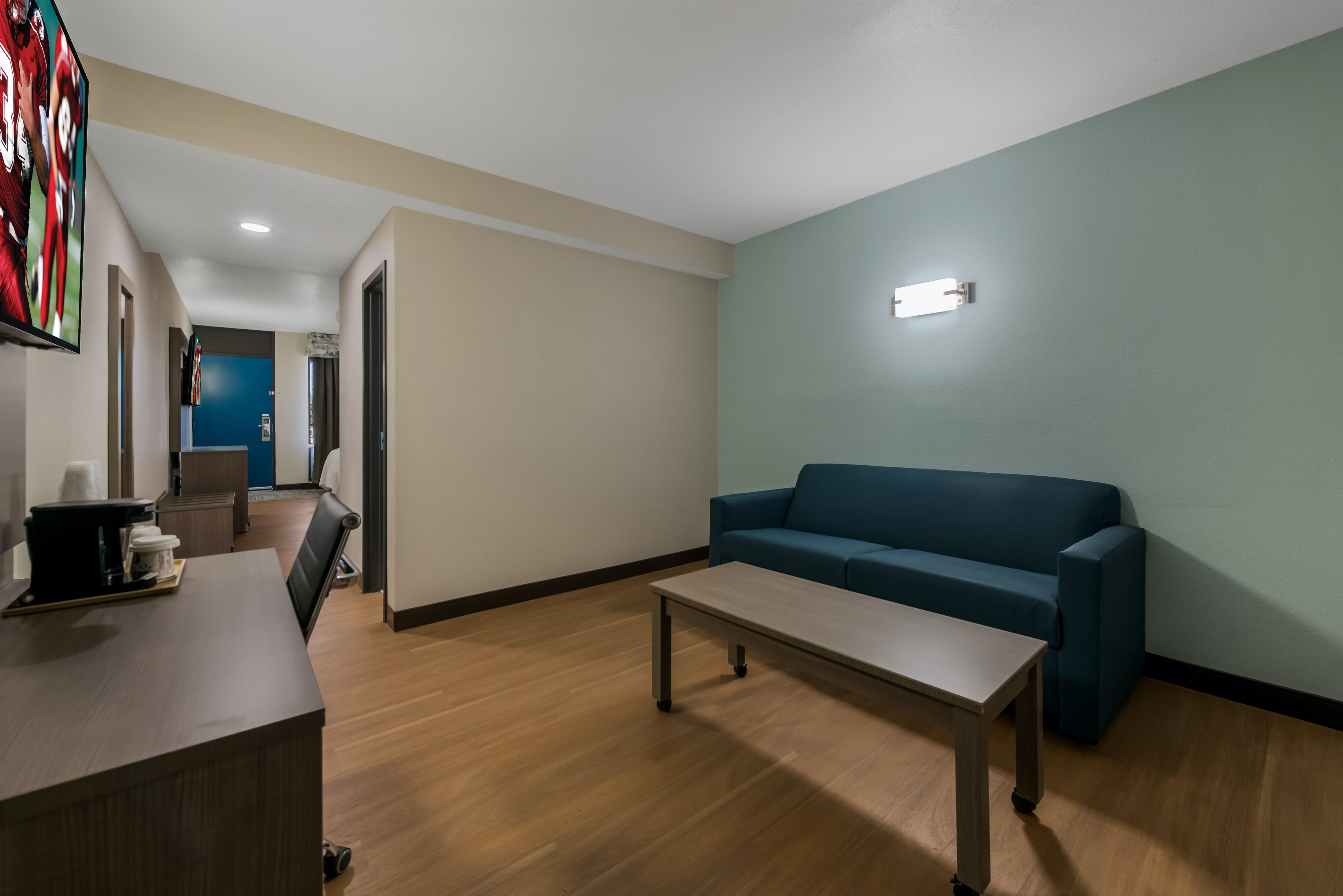 A modern living room with a sofa, a coffee table, and a flat-screen TV mounted on the wall.