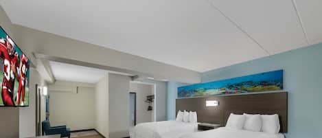 Habitación de hotel con dos camas, un escritorio, una silla y un televisor mostrando deportes.