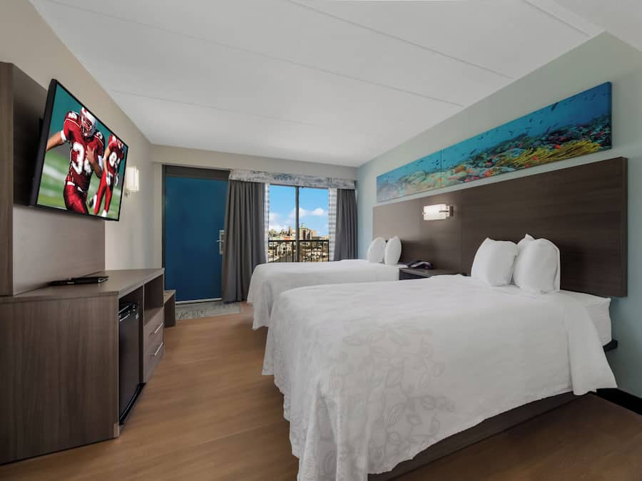 Une chambre d’hôtel avec deux lits, une télévision, un tableau et une vue sur la ville.
