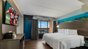 A hotel room with a large bed, a television on the wall, and a painting of an underwater scene. - Red Roof Inn PLUS+ & Suites Virginia Beach – Seaside (Virginia Beach)