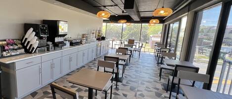 A modern cafe with a counter, seating area, and large windows.