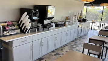 Un café moderno con una barra larga, máquinas de café y zona de estar.