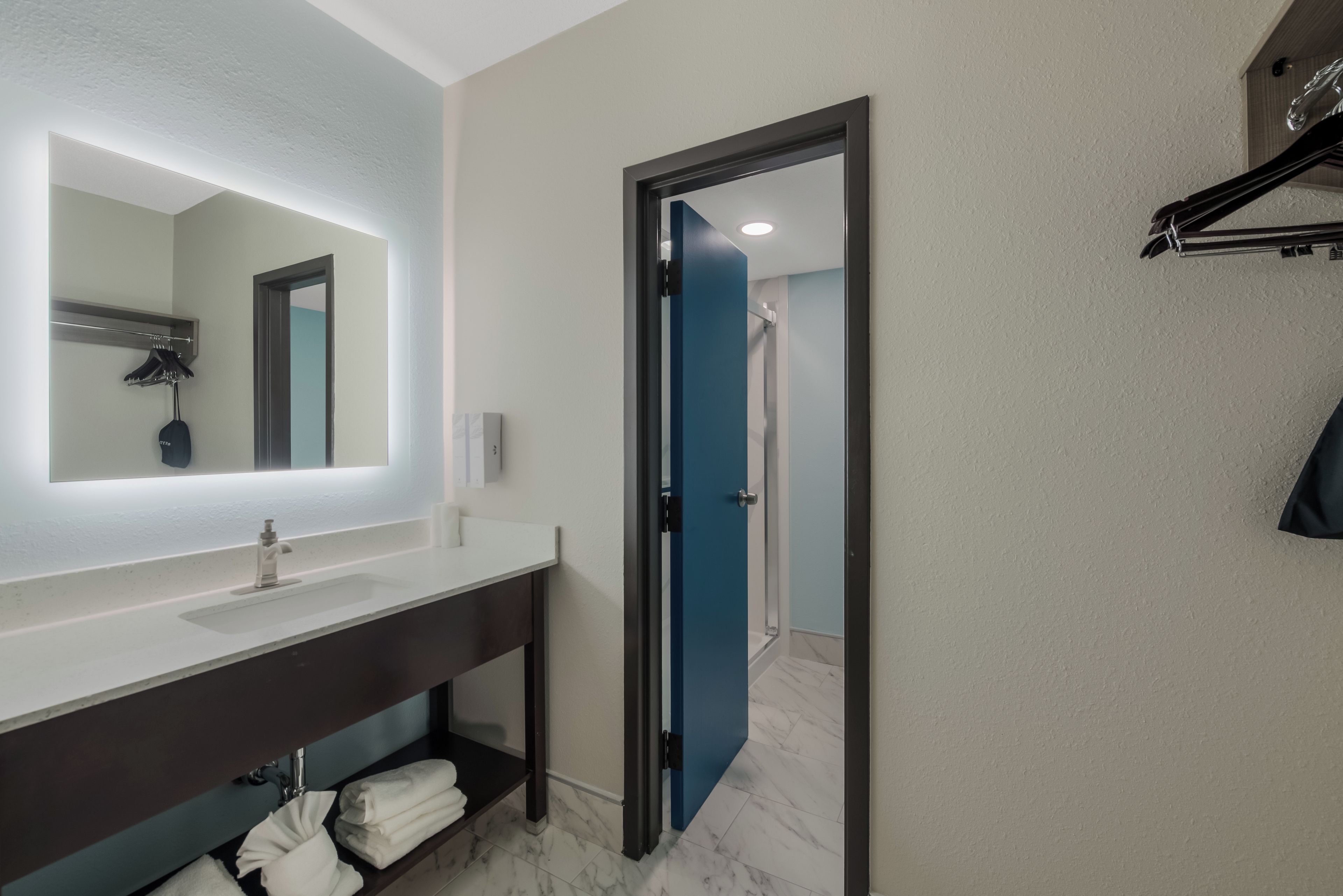 Une salle de bain moderne avec un grand miroir, un lavabo et un espace douche.
