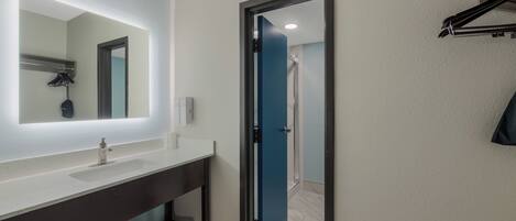 Une salle de bain moderne avec un grand miroir, un lavabo et un espace douche.