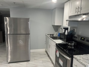 A kitchen with stainless steel appliances, white cabinets, a black stove, and a granite countertop. - Red Roof Inn PLUS+ & Suites Virginia Beach – Seaside (Virginia Beach)