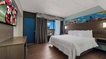 Una habitación de hotel con una cama, un escritorio, un televisor y un mural en la pared.