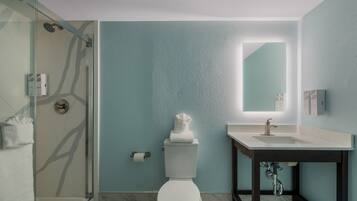 A modern bathroom with a glass-enclosed shower, a white toilet, a sink with a mirror, and marble flooring.