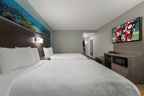Quarto de hotel com duas camas, televisão, micro-ondas e um quadro na parede.