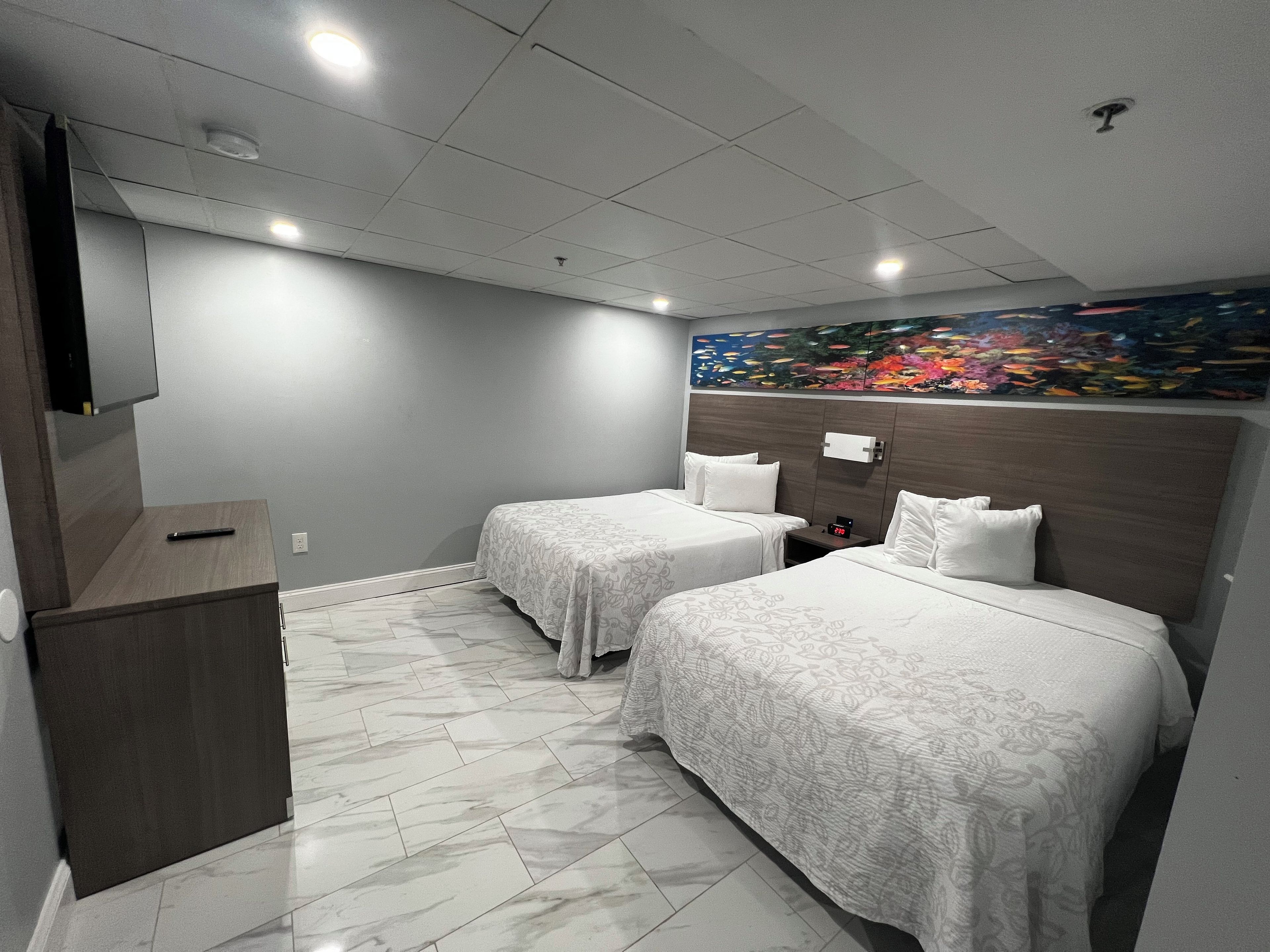 A hotel room with two beds, a nightstand, a TV, and a painting on the wall.