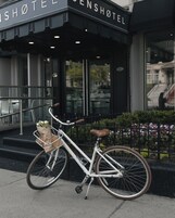Una bicicleta con cestas y flores estacionada frente a la entrada de un hotel.