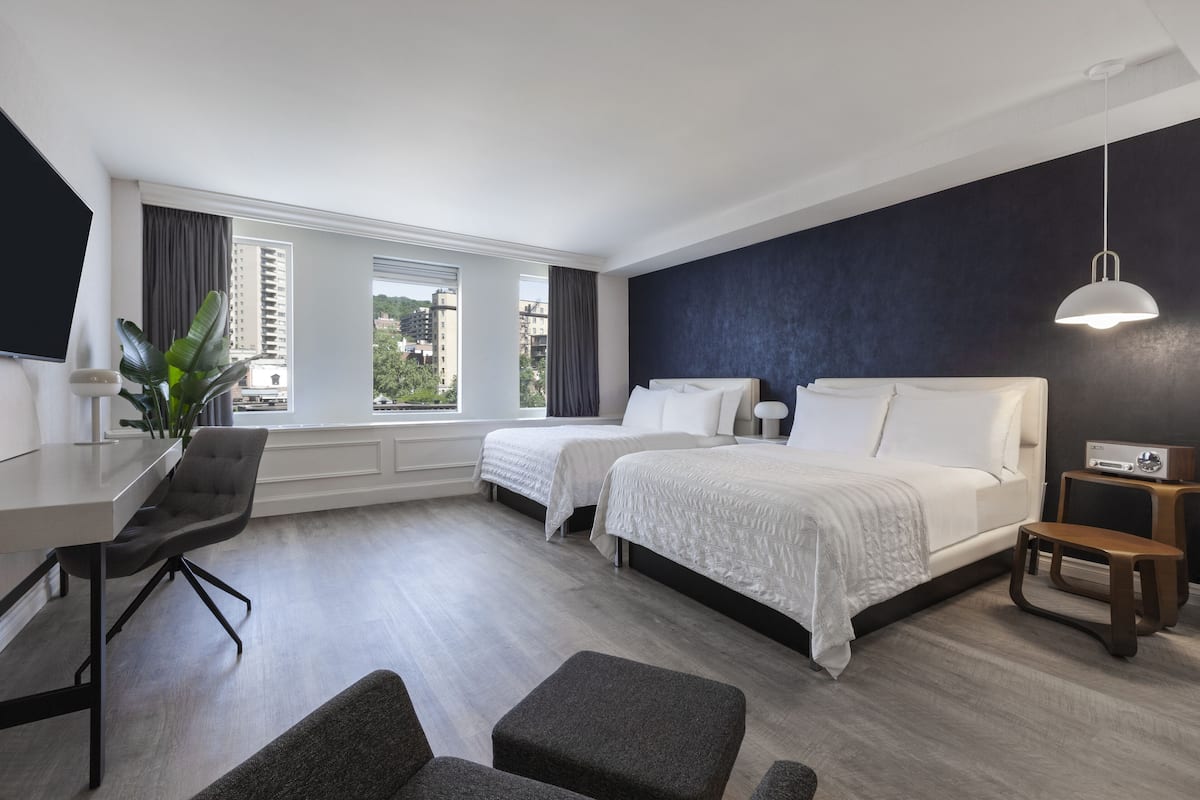 A modern hotel room with a large bed, two bedside tables, a desk, and a chair.