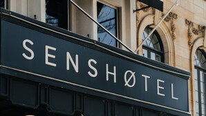 A sign for 'SENSHOTEL' with a classic architectural backdrop. - SENS Hotel (Montreal)