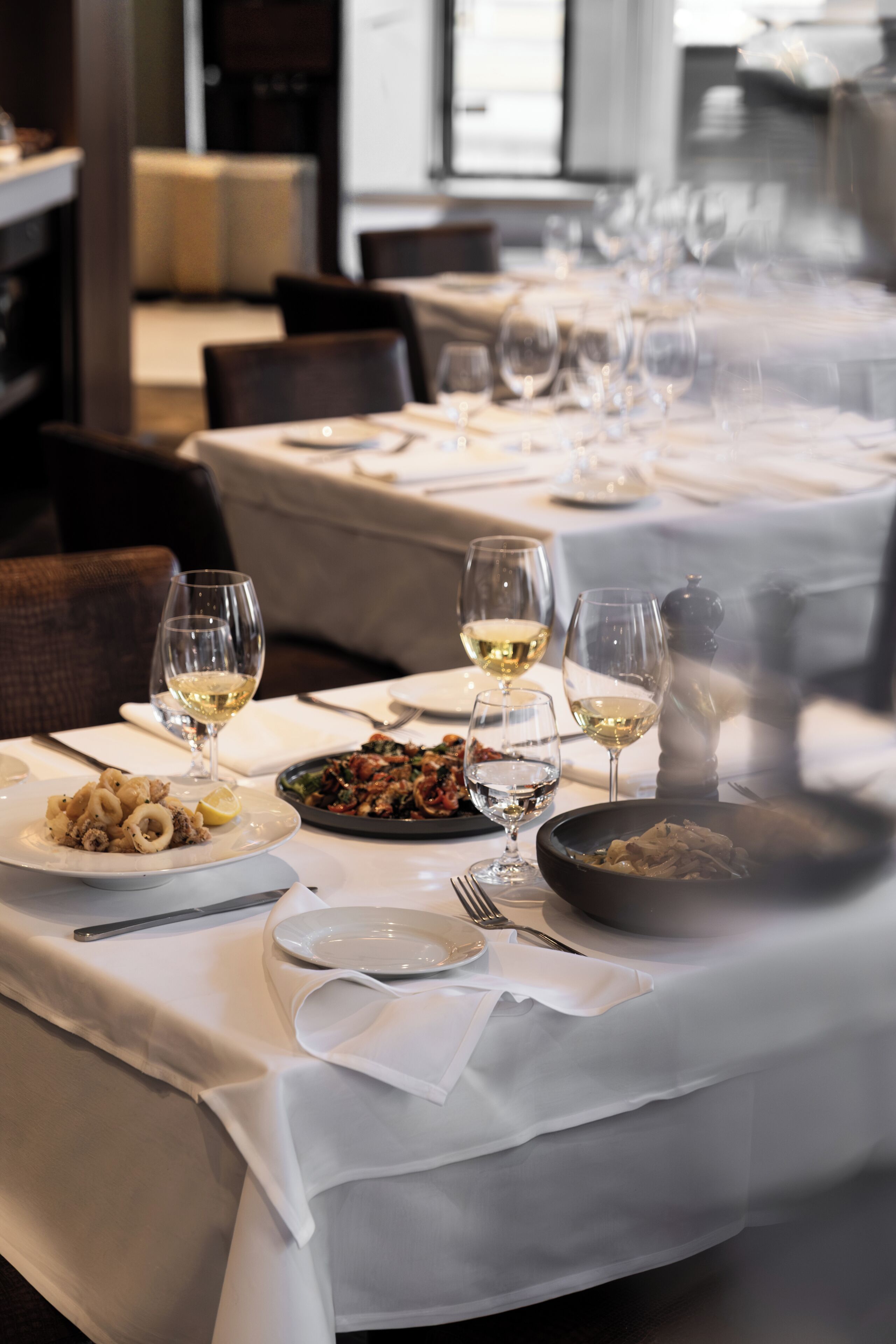 Mesa puesta con platos, vasos y cubiertos, lo que sugiere un ambiente de restaurante.