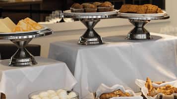 Une table de buffet proposant divers plats, notamment des pâtisseries, du pain et un saladier d’œufs.
