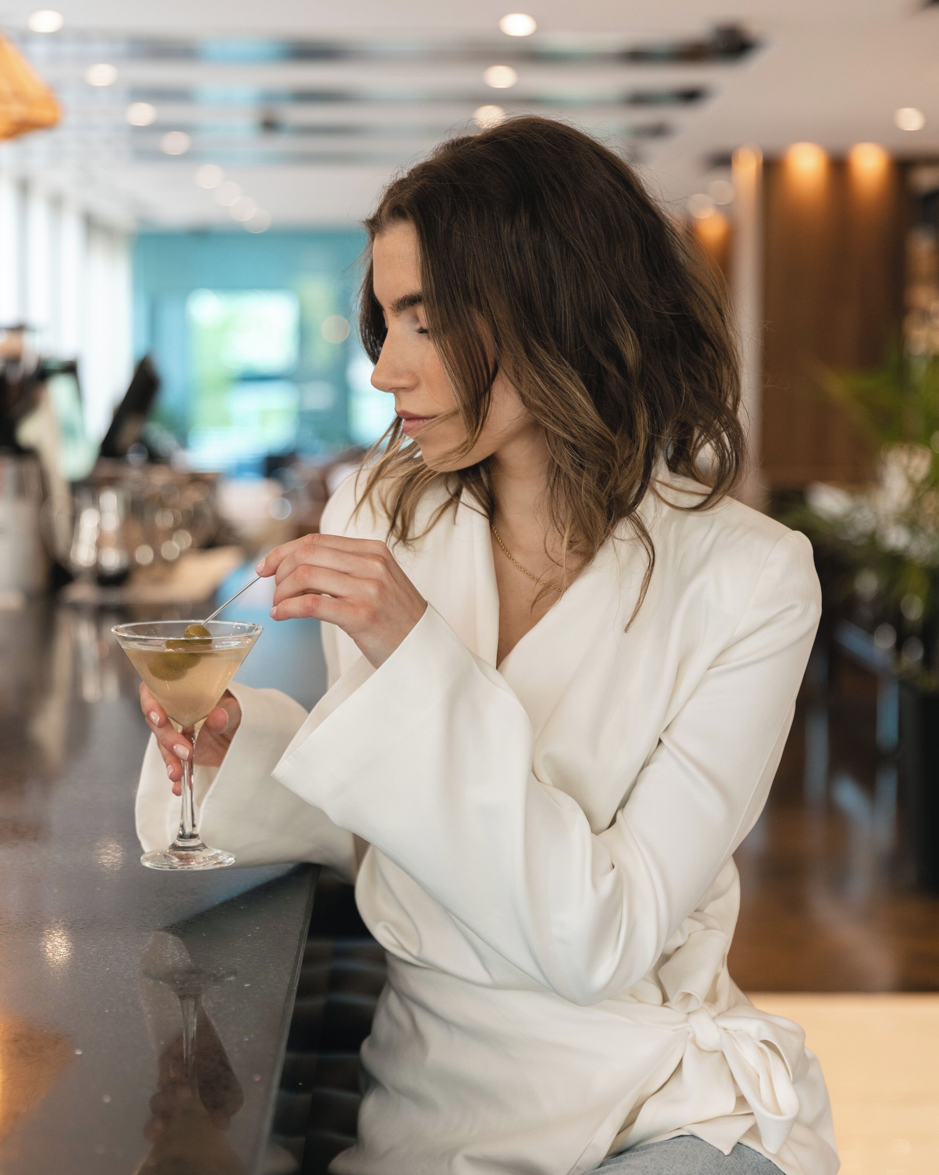 A person seated at a bar with a drink in hand.