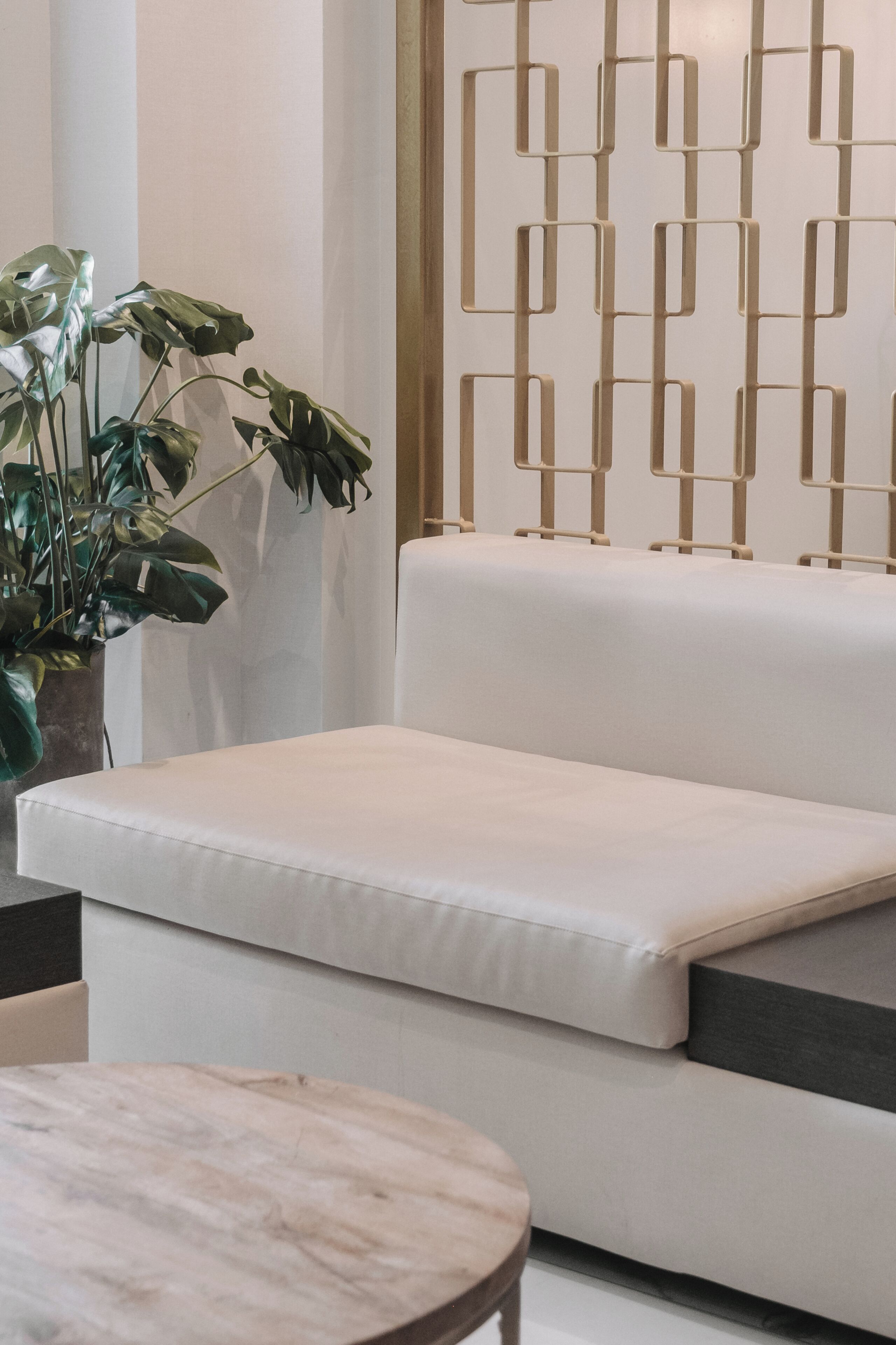 Un salon moderne avec un canapé blanc, une table ronde en bois et une plante en pot.