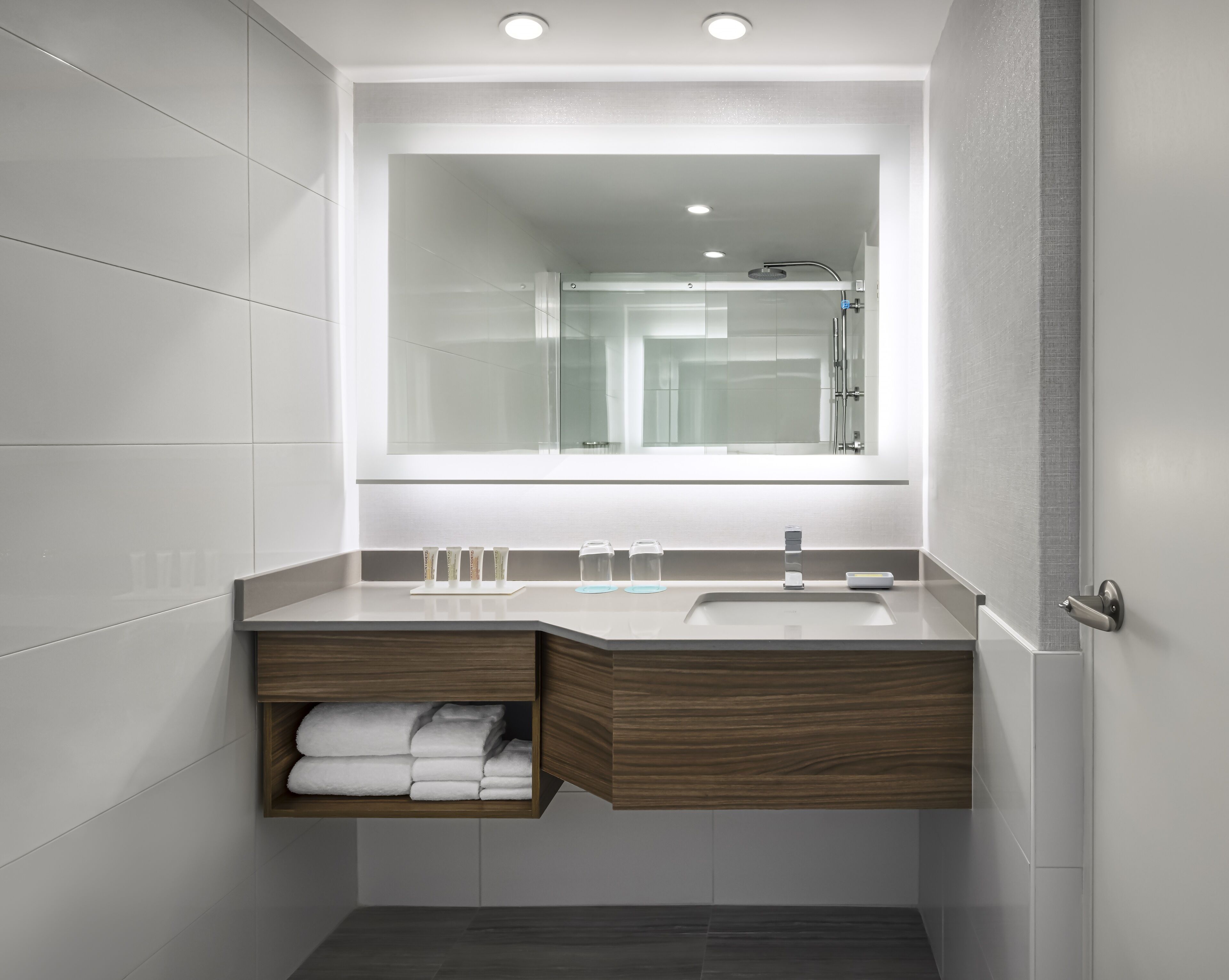 A modern bathroom with a built-in sink, a mirror, and a shower.