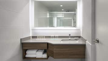 A modern bathroom with a built-in sink, a mirror, and a shower.
