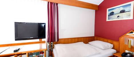 A hotel room with a wooden bed, a television, a desk with a chair, and a painting on the wall.