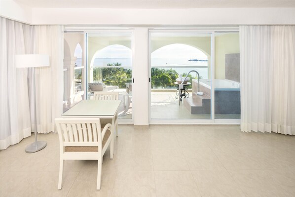 A hotel room with a balcony, a dining area with a table and chairs, and a view of the ocean. - Occidental Costa Cancún All Inclusive (Cancun)