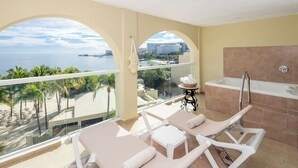 Ein Balkon mit Liegestühlen, Blick auf das Meer und einer Badewanne.